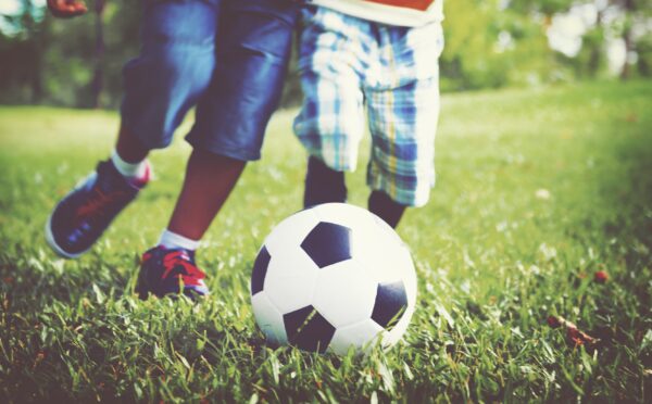 kids-playing-football-grass-min
